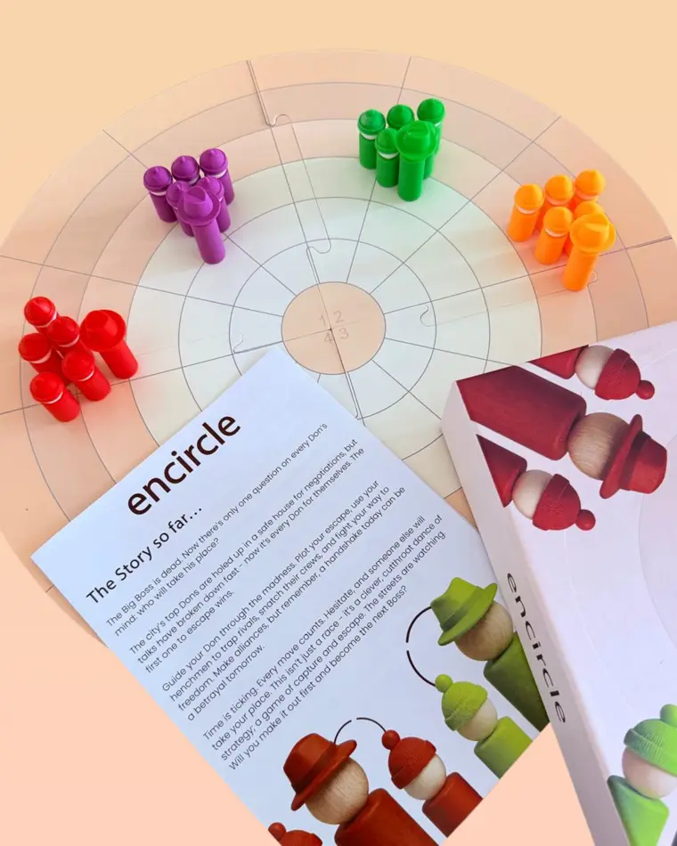 The Encircle box and rulebook on the board with pieces